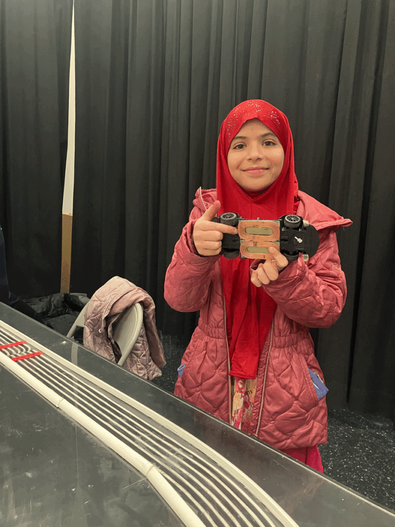 Abdulla Baig's daughter holding up a model car at the STEM fair.