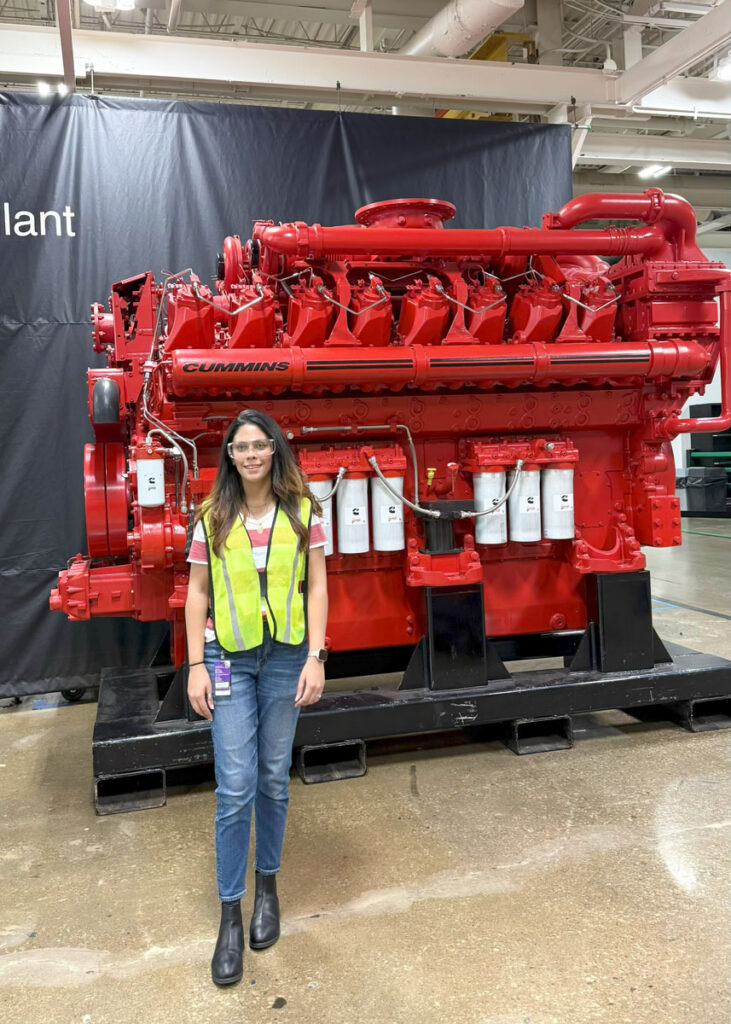 Zainab Imram smiles in front of red equipment at her internships at Cummins.