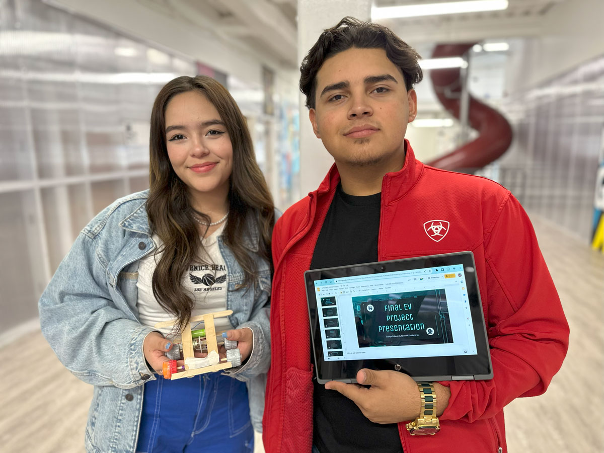 Students hold up their model EV and presentation as a part of the ASPIRE curriculum.