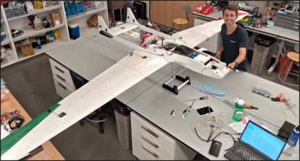 Jon Silberstein, one of the lead authors of the paper, working on the project. The wings of a model plane can be seen extending on either side of a work table.