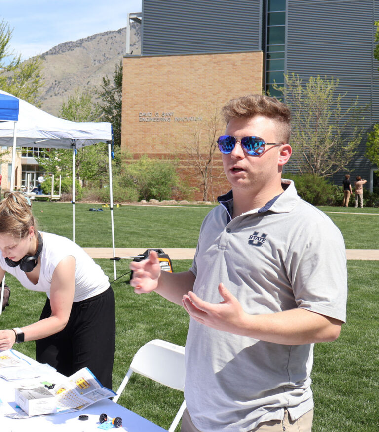 Mackay Baugh at a table explaining his research during USU's Research Week.
