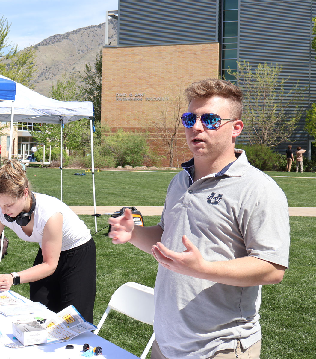 Mackay Baugh at a table explaining his research during USU's Research Week.